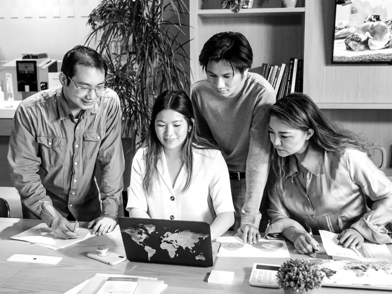 A team gathered around a table reviewing sketches and printed layouts together