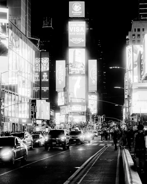 Busy city street at night lined with large illuminated digital billboards